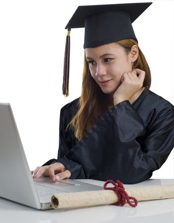 Young woman with graduation cap and gown using notebook computerの写真素材