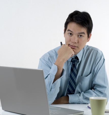 Asian businessman sitting and thinking at his deskの写真素材