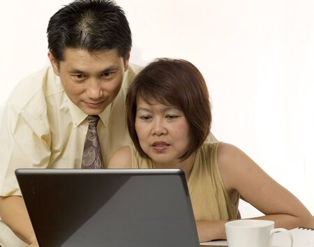 Middle age Asian couple using computer for internetの写真素材