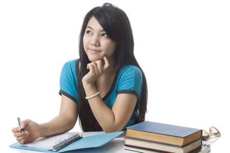 Young attractive female Asian student daydreaming and doing homeworkの写真素材