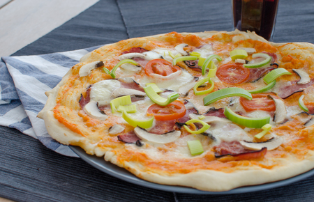 Home made pizza with pork, tomato, salami and sodaの写真素材