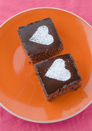 Chocolate cake with heards from sugar on plate, pink bachgroundの写真素材