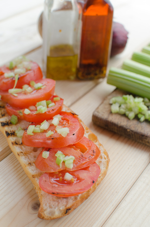 grilled baguette with grilled tomatoes, olive oil and cutted celeryの写真素材