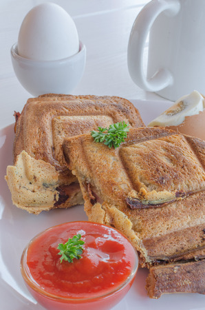 Toasts and egg with souce on white plate and woodの写真素材