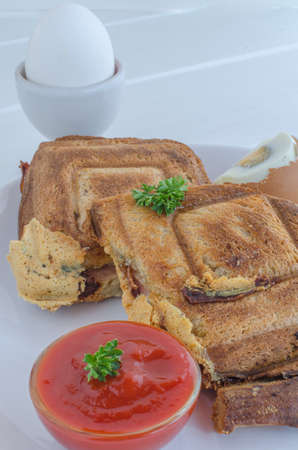 Toasts and egg with souce on white plate and woodの写真素材