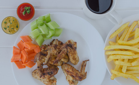 Chicken wings with french fries,sauce and vegetablesの写真素材