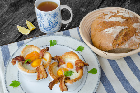 Muffins with eggs and bacon with black tea and lemonの写真素材