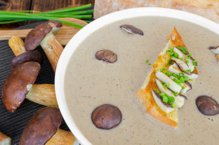 Mushroom cream soup with toast and fresh herbs on wood tableの写真素材