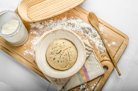 Making bread home in a basket - scuttle on white tableclothの写真素材