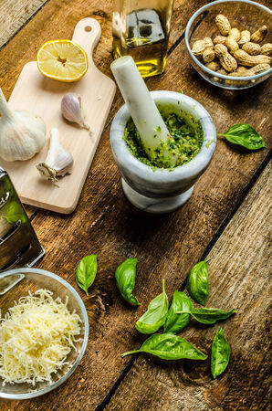 Making pesto - basil cheese, nuts, and olive oil in mortarの写真素材