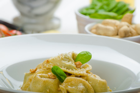 Homemade tortellini stuffed with spinach and garlic, topped with lightly buttered reduction with nutsの写真素材