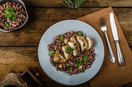 Roasted chicken breast with herbs and stewed beans, bio garlic roasted with wine and olive oil on top, fresh herbs, old school pictureの写真素材