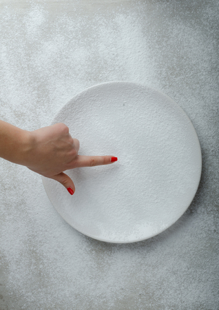 Snowy plate background with a woman hand, winter timeの写真素材