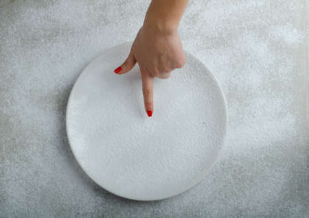 Snowy plate background with a woman hand, winter timeの写真素材