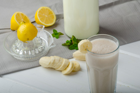 Homemade banana smoothie with lemons, herbs and organic milk from the farmの写真素材