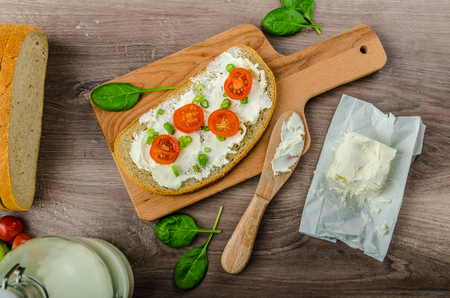 Fresh bread smeared with cream cheese, cherry tomatoes and spring onions, milk from farmの写真素材