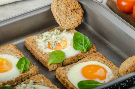 Baked Bull's-Eye Eggs on whole wheat toast with spinach and blue cheese on top