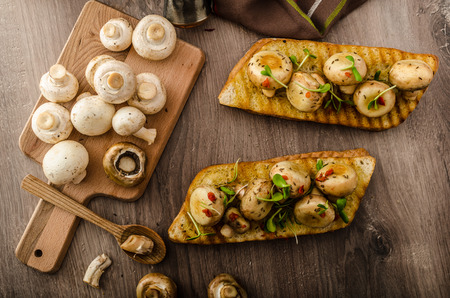 Wild mushrooms on baked toast with microgreens and chilliの写真素材