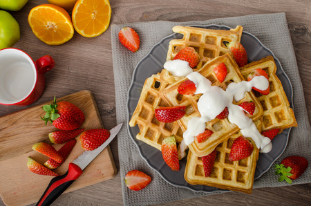 Homemade waffles with maple syrup and strawberries, topped fresh cream, orange fresh beverageの写真素材