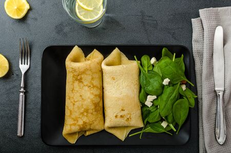 Spinach pancakes with feta cheese, simple drink with lemon, clean tableの写真素材