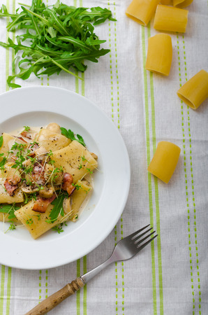 Italian rigatoni with parmesan cheese, parma ham and mushrooms, arugula and microgreens sprinkledの写真素材