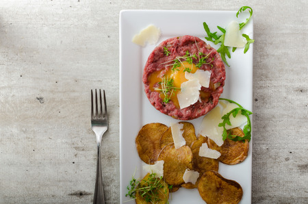 Beef tartar, homemade potato chips, sprinkled with parmesan shavings and microgreensの写真素材