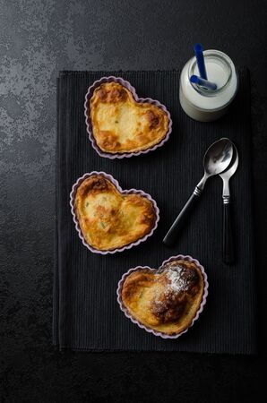 Valentine's Day mini heart-shaped tart with lemon and creame, clean black composition, milk and spoonsの写真素材