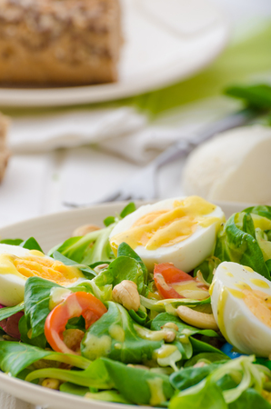 Lamb's lettuce salad with roated cashews, sunflower nuts, pumpkin nuts, boiled eggs on top, healthy breadの写真素材