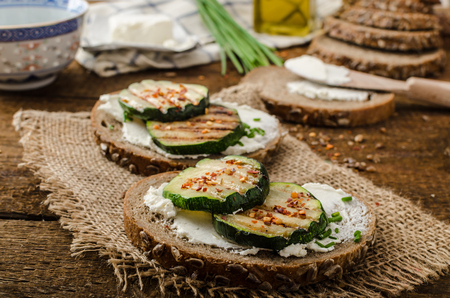 seeds bread spread by cream cheese and grilled zucchini and chilli flakes, with chiveの写真素材