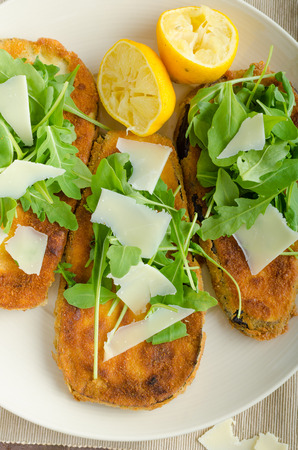 Fried breaded eggplant with salad of arugula topped with parmesan cheeseの写真素材