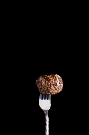 Meatball on black background on forkの写真素材