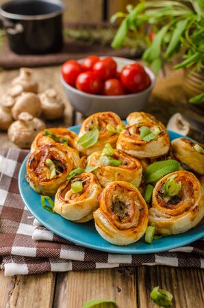 Pizza snails in puff pastry with ham, cheese and mushroomsの写真素材