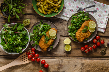 True Viennese schnitzel with little salad and lime, french fries and beautiful cherry tomatoesの写真素材