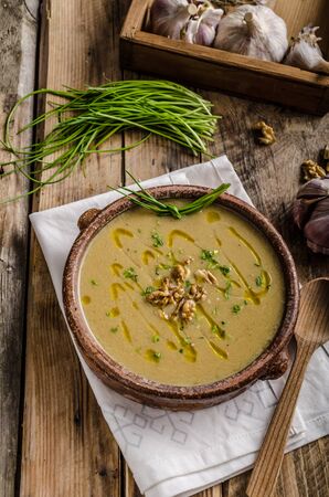 Cream soup of parsley root, with olive oil, baked nuts, garlic and chiveの写真素材