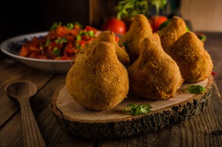 Delicious food consisting of chopped or shredded chicken meat, covered in dough, molded into a shape resembling a chicken leg, battered and fried, with hot salsa, rustic photoの写真素材