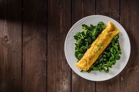 French omelet, fluffy, fresh eggs and herbs on wood boardの写真素材