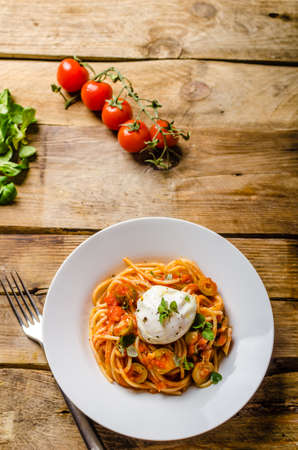 Italian tomato spicy pasta with poached egg and fresh herbsの写真素材
