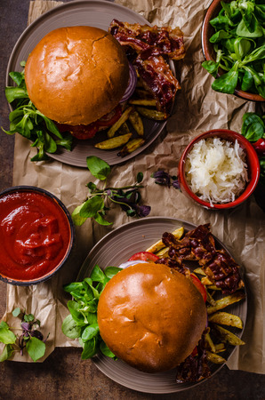 Beef burger with bacon and home french fries, little salad and hot sauce.の写真素材