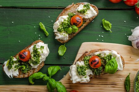 Grilled toasts with mozzarella, tomatoes and homemade pesto, vegetable on skewersの写真素材