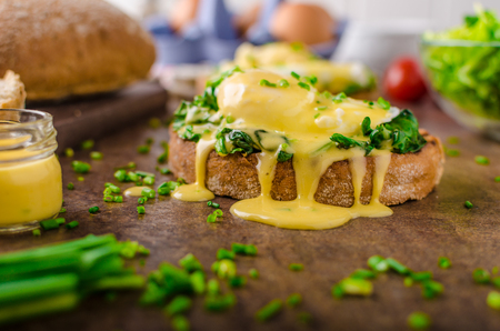 Egg benedict - rustic bread with poached egg and garlic spinach, topped with delicious hollandaise sauceの写真素材
