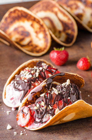 Homemade tacos with ice cream, nuts and chocolate, delicious strawberriesの写真素材