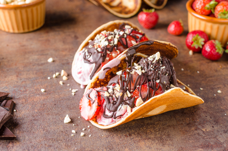 Homemade tacos with ice cream, nuts and chocolate, delicious strawberriesの写真素材
