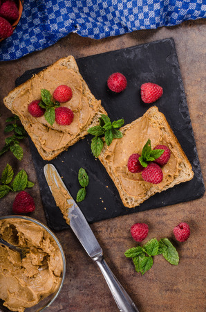 Toast with peanut butter and berries, rustic composition, styled with mint, homemade peanut butterの写真素材