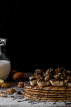 Rustic pancakes with banana and chocolate, roasted nuts on topの写真素材