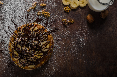 Rustic pancakes with banana and chocolate, roasted nuts on topの写真素材
