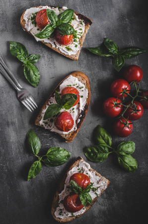 Bread cheese spread baked tomato, fresh basil on topの写真素材