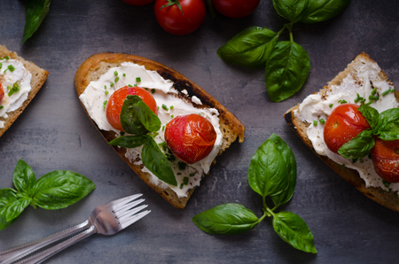 Bread cheese spread baked tomato, fresh basil on topの写真素材