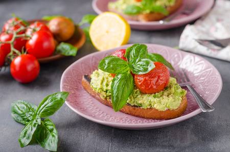 Avocado spread bread with baked tomato salad, fresh basilの写真素材