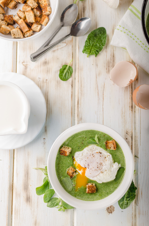 Spinach soup with poached egg, fresh croutons and herbsの写真素材