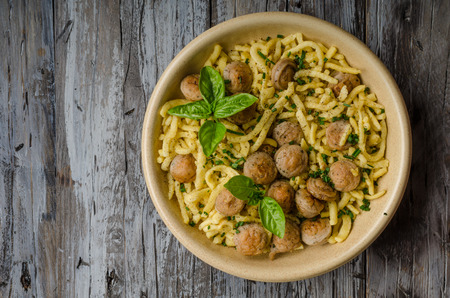 Homemade spaetzle, barbecue sausage and fresh cheese, herbs on rustic wood board, food photographyの写真素材